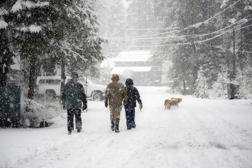 A family walks with their dog during heavy snow near Donner Lake in Truckee in California on Christmas Eve